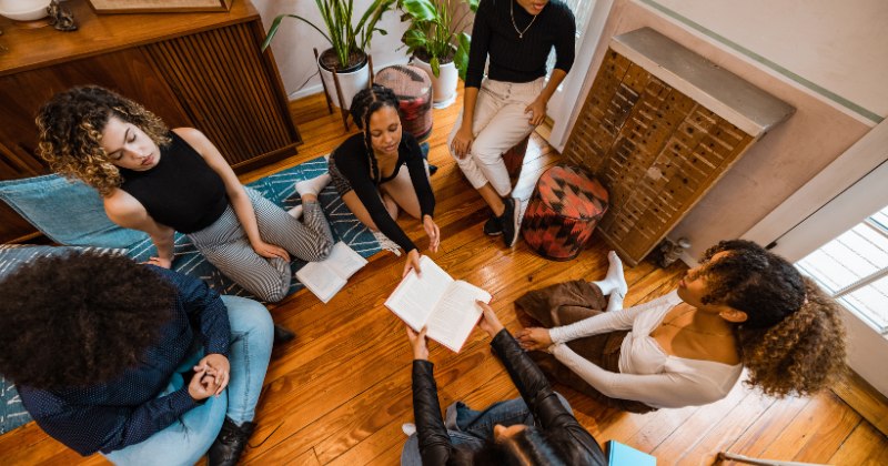 A group of female college students talking and sitting in a circle with books