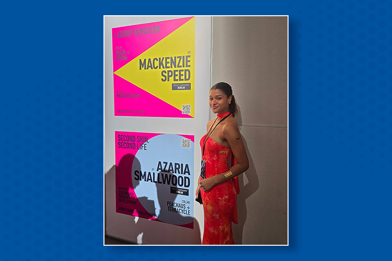 College student in a formal red dress standing next to a sign with her name: 