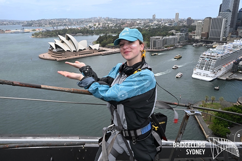 A college student standing at the top of a bridge overlooking a harbor in Sydney, Australia.