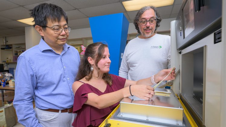 Michelle Yatvitskiy, a recent graduate of the fashion and apparel studies master’s program (center), holds a strip of a new fabric for the outer layer of space suits that was the result of a collaboration between the fashion and chemical engineering departments and a company founded by Blue Hen alumni. Yatvitskiy is accompanied by Huantian Cao, chair of the Department of Fashion and Apparel Studies, and chemical engineering professor Norm Wagner 