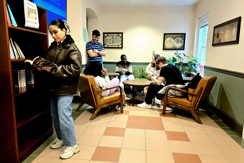Group of graduate students studying near a window with their open laptops
