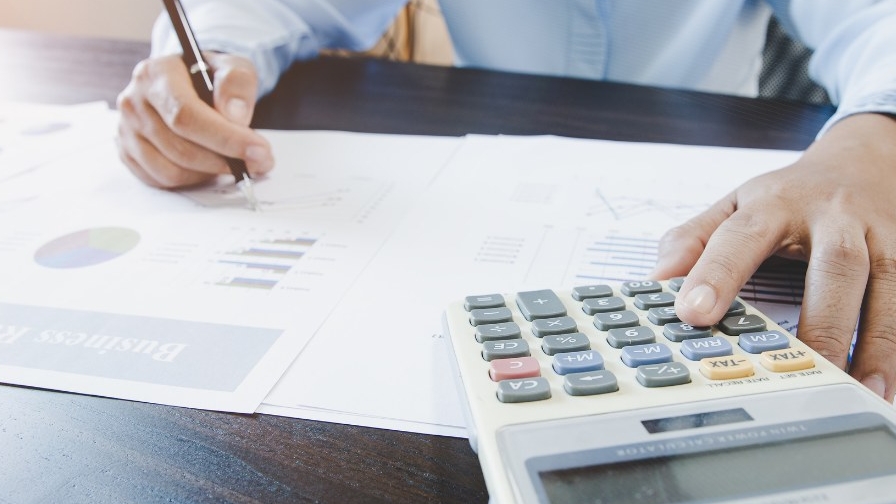 A photo of hands writing and using a calculator