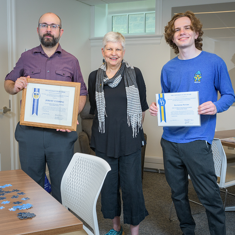 Donor Molly McKaughan stands between the two recipients of the Nicholas Fremont Plummer Philosophy Prize, who are holding their certificates.