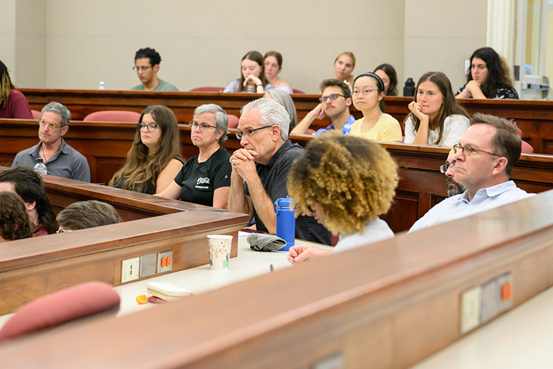 Audience in a lecture hall listens attentively.