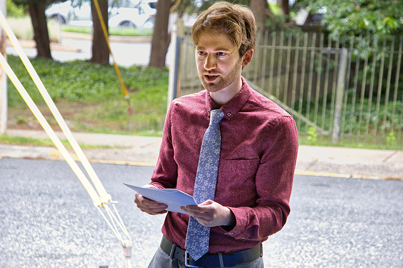 A University of Delaware philosophy alumnus delivers remarks at an outdoor event.