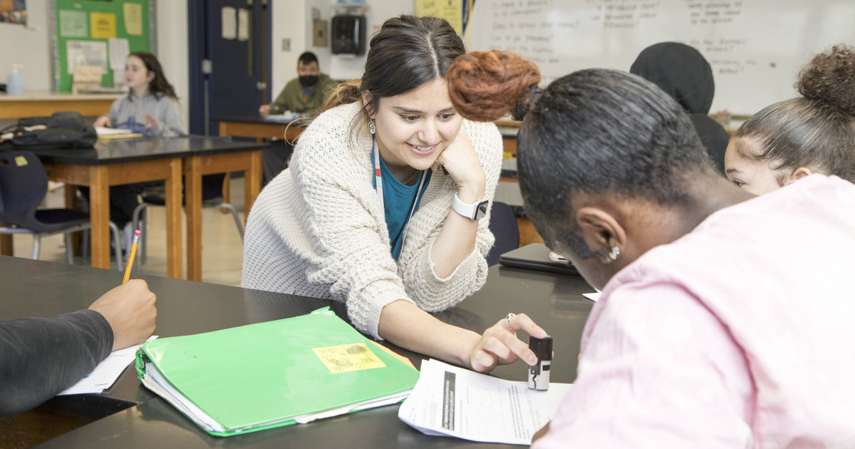 A University of Delaware student teacher checks a high school student's work during a class in Wilmington, Delaware. 