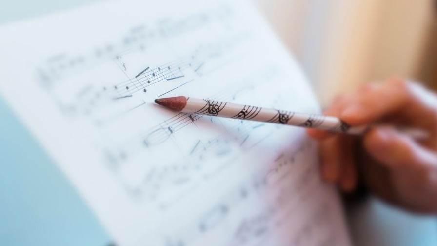 Pencil pointing at a piece of music composition on a stand