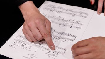 Music composition faculty with student pointing at music on paper