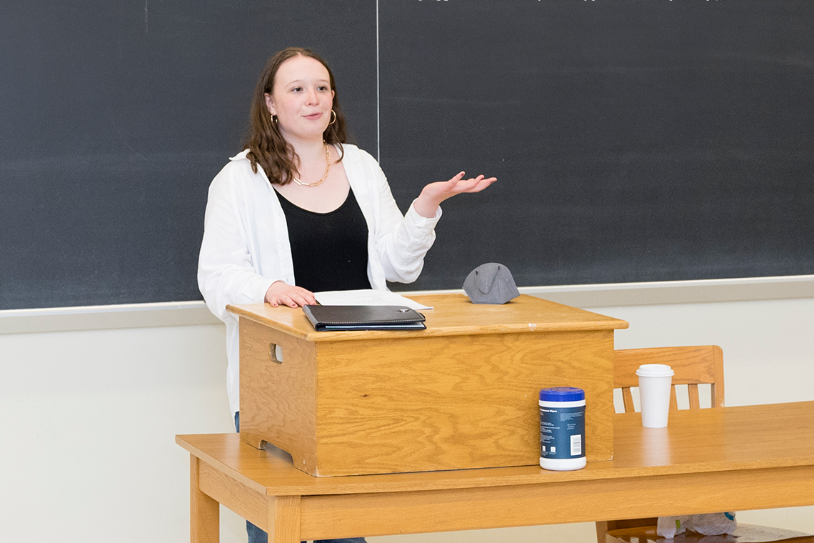A female University of Delaware student presents her research inside a classroom.