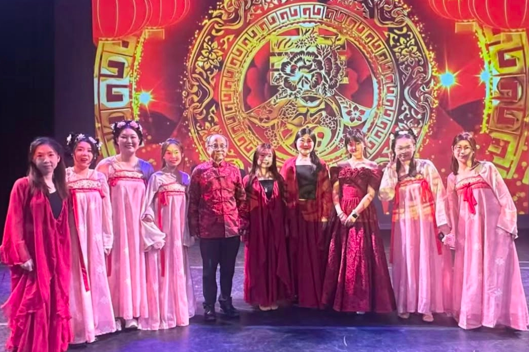 Students stand on stage in traditional Chinese attire after a dance performance.