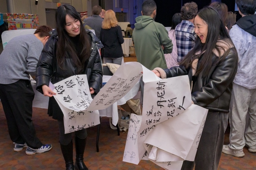 Two Chinese students hold papers full of calligraphy at the Festival of Nations.