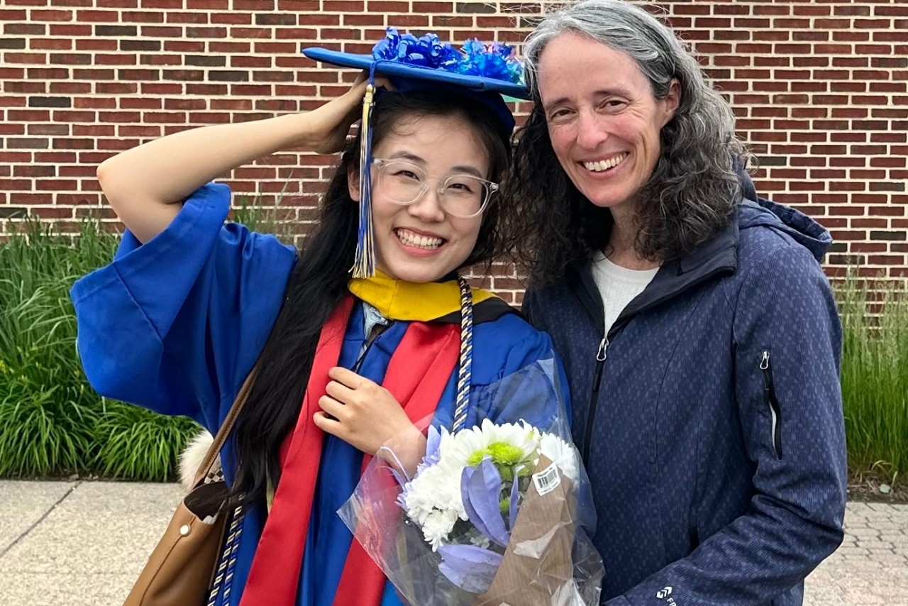 Wanning Wang stands in her graduation cap and gown with Julie Lopez, A-UD academic advisor.