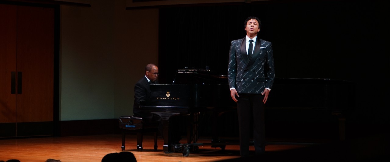 Man playing a piano and another man singing
