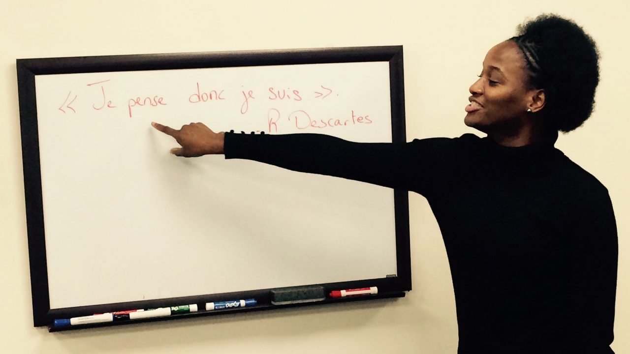 Female Black student teacher pointing to french words on a white board