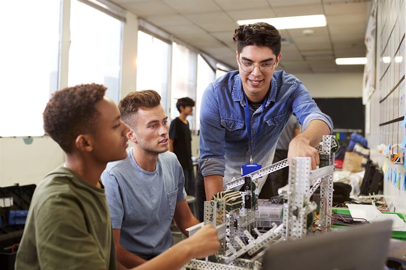 Student teacher assisting two students in a lab classroom