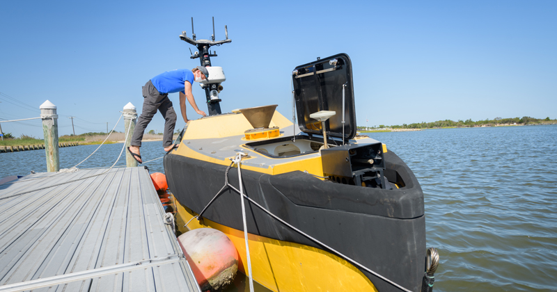 Grant Otto, a master’s student at UD, is pictured with one of Ocean Infinity’s Seaworker autonomous surface vessels (ASVs) stationed at UD’s Hugh R. Sharp Campus in Lewes. Otto helped in the search for the sunken tugboat Miss Aida.