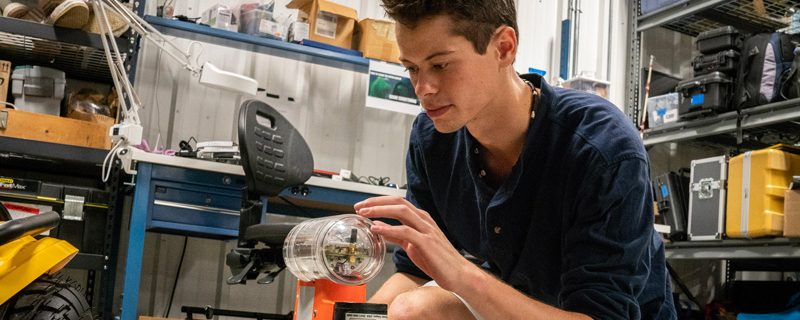Undergraduate student examines machine in Robotics Discovery Laboratory