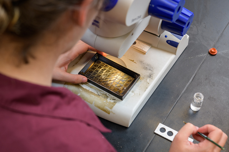 Grad student examining precious metal under microscope