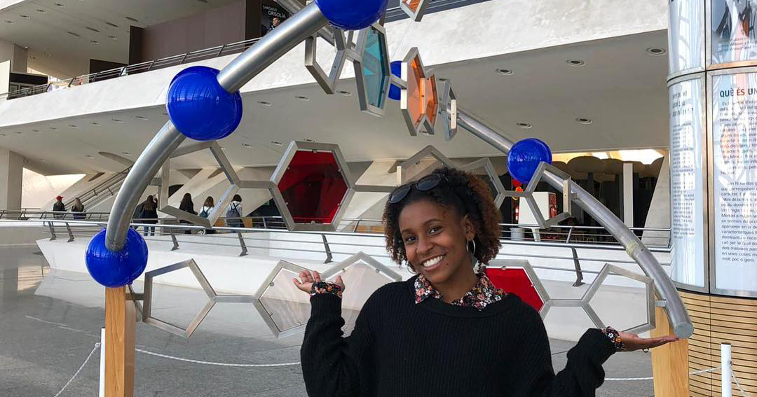 Briyana Chisholm stands in front of a molecule statue