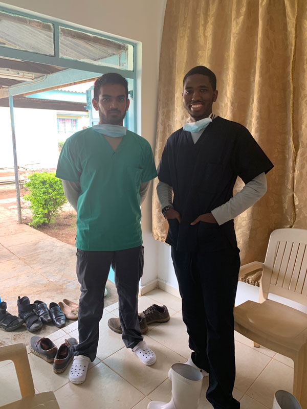 Jordan and Darshil wear scrubs in a location where they did a mission trip to Kenya