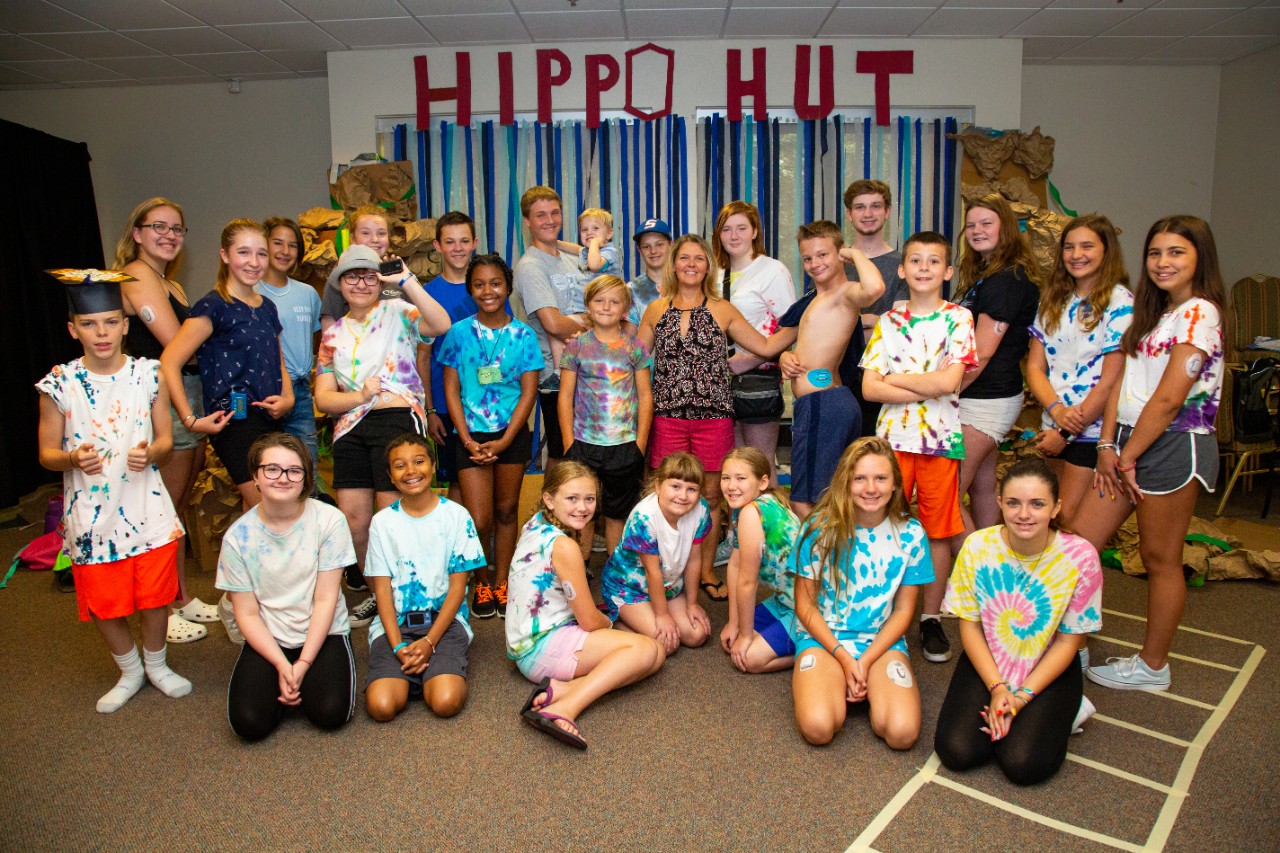 A group of kids in tie dye T-shirts pose with Jen Saylor during a diabetes camp