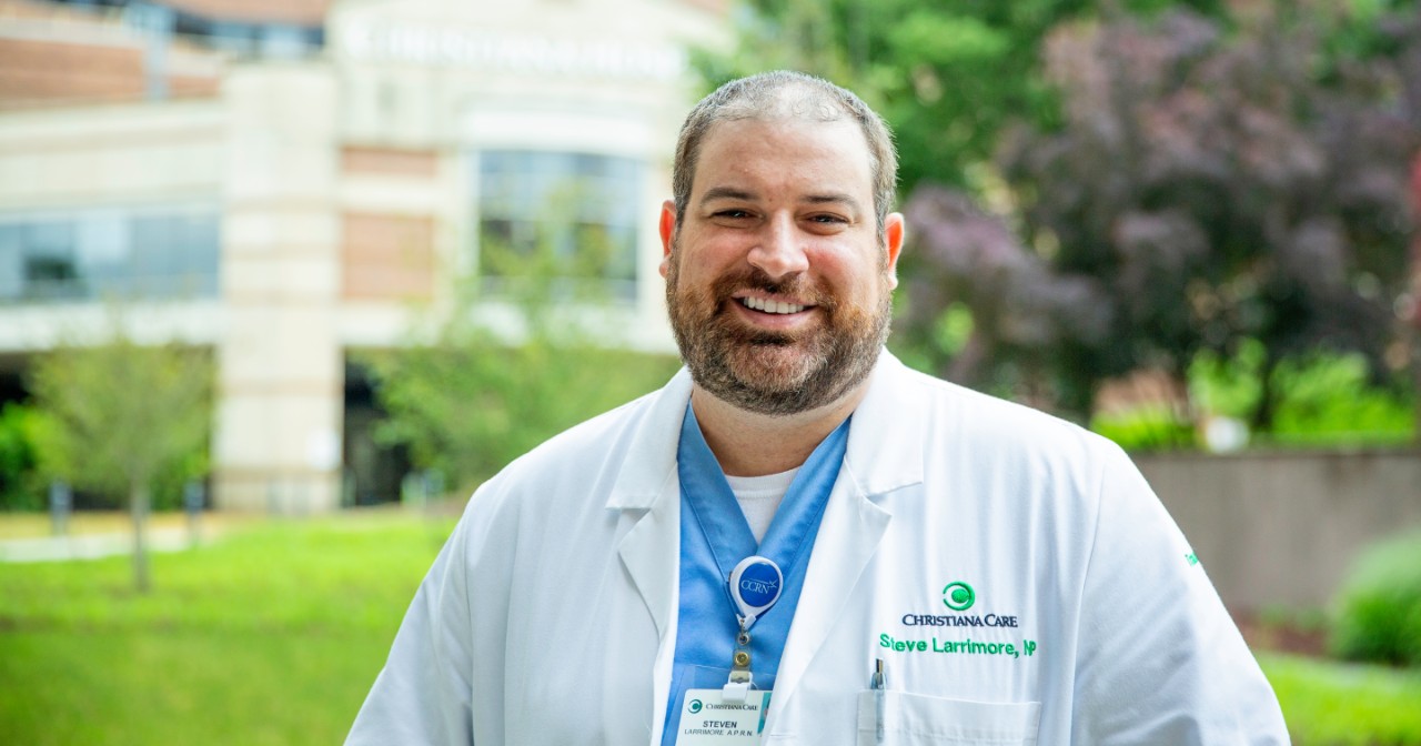 Steve Larrimore wears a white NP coat and stands in front of Christiana Hospital