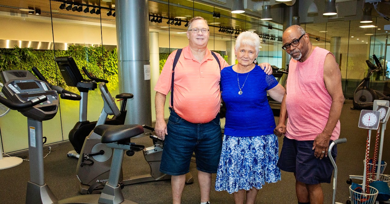 A trio of renal rehab participants stands together in the exercise space in the Tower at STAR