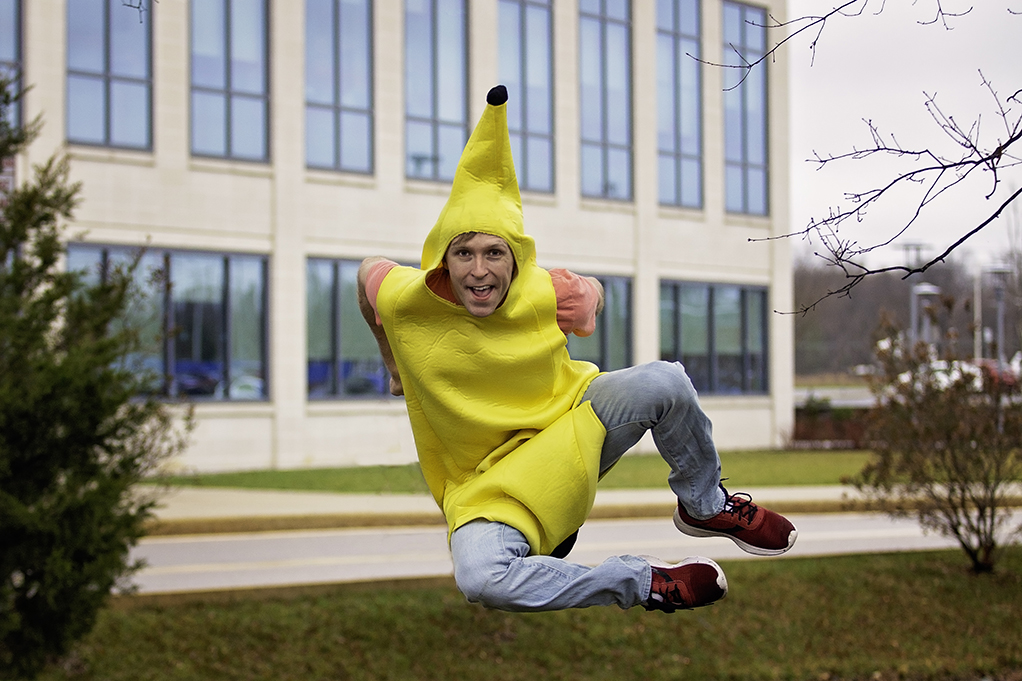 Taylor Darden wears a banana suit and does a heel kick in the air outside of STAR Campus