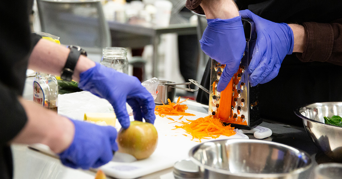 Behavioral Health and Nutrition students slice an apple and grate carrots for a healthy eating recipe.