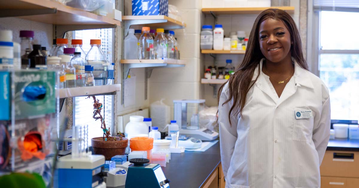 Roxanne Evande standing beside a lab counter with scientific equipment