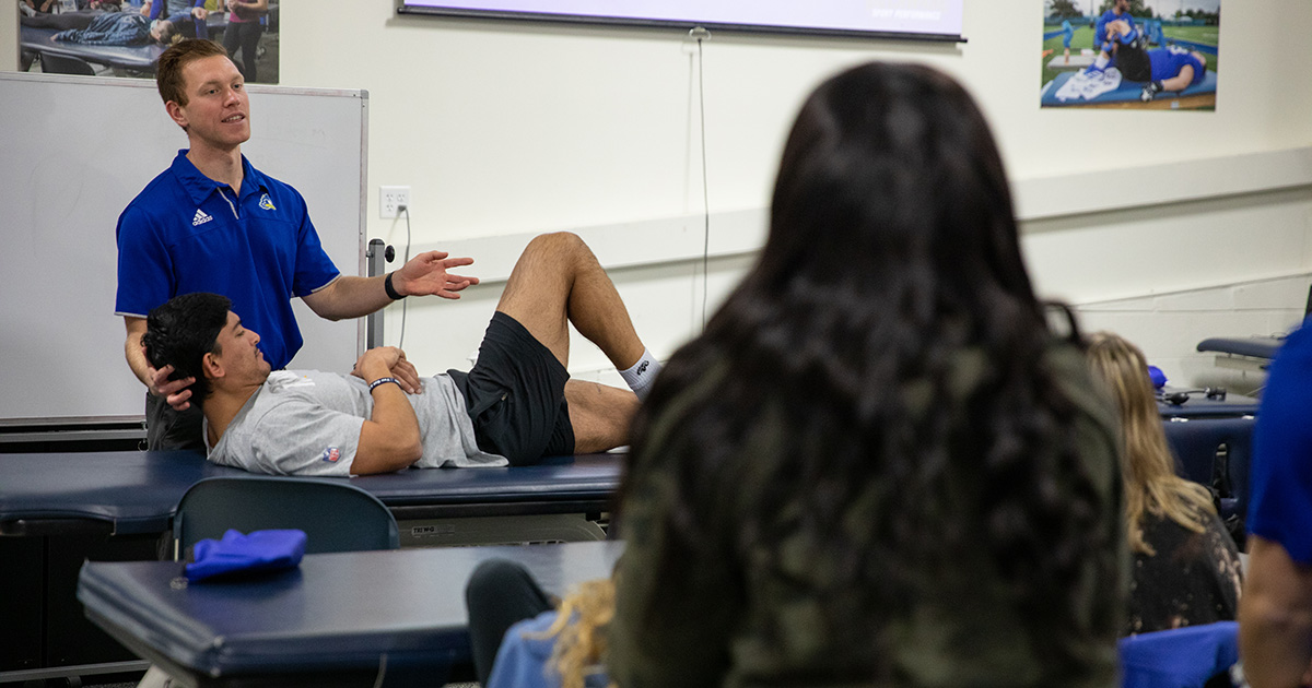 An athlete stretches in a lower extremity spine class for students in the athletic training education program.