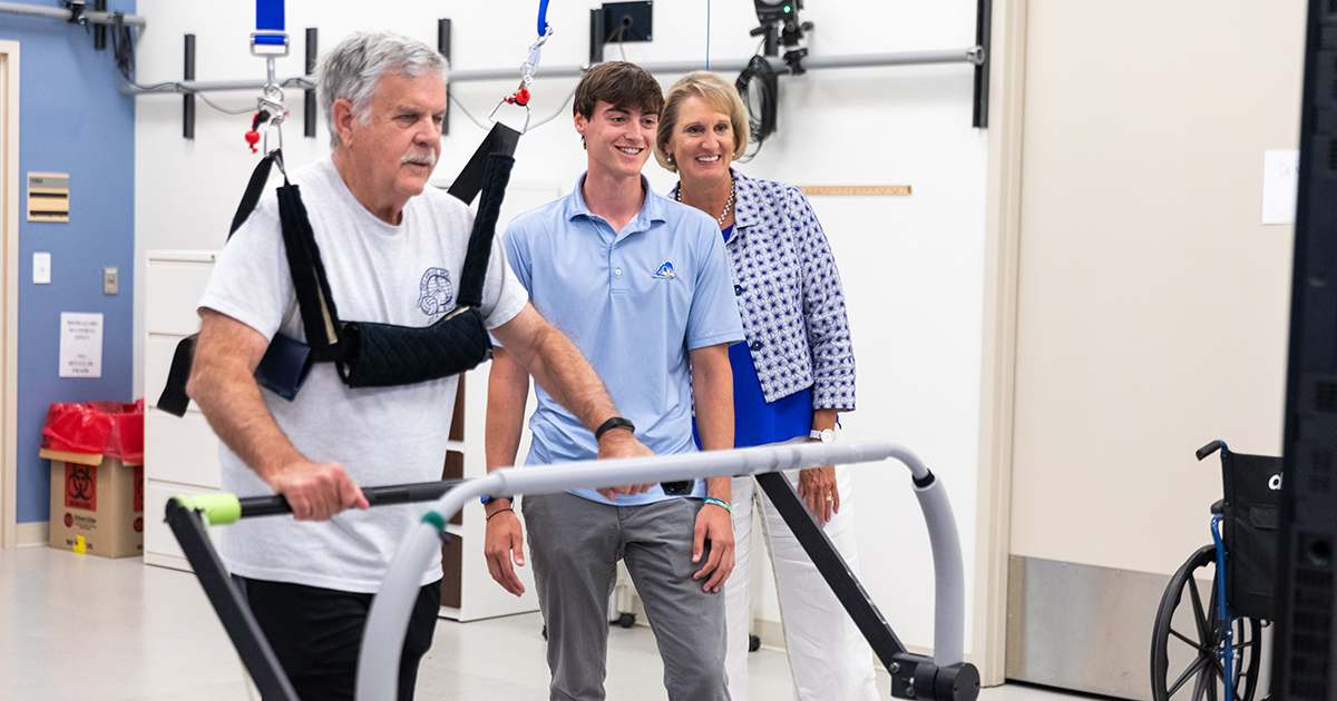 A stroke survivor walks on an adaptive treadmill as part of stroke recovery research. Dr. Darcy Reisman, professor of physical therapy, and Peter White Fellow Matt Carr watch as data is collected.