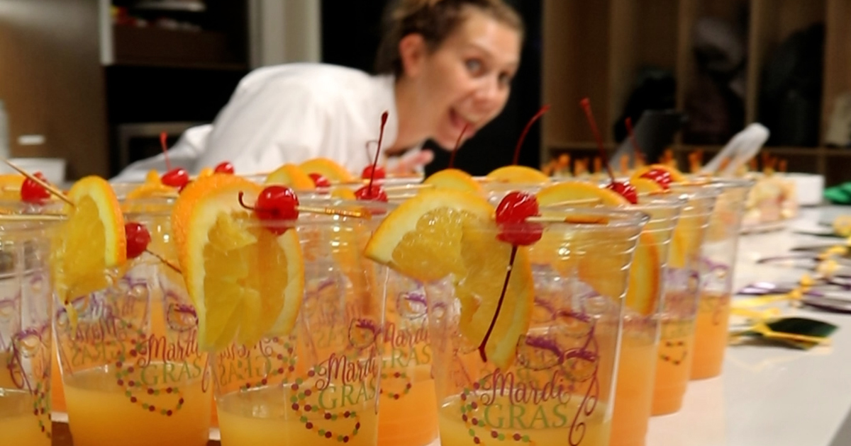 Jen Muzzi smiling behind a row of orange juice drinks