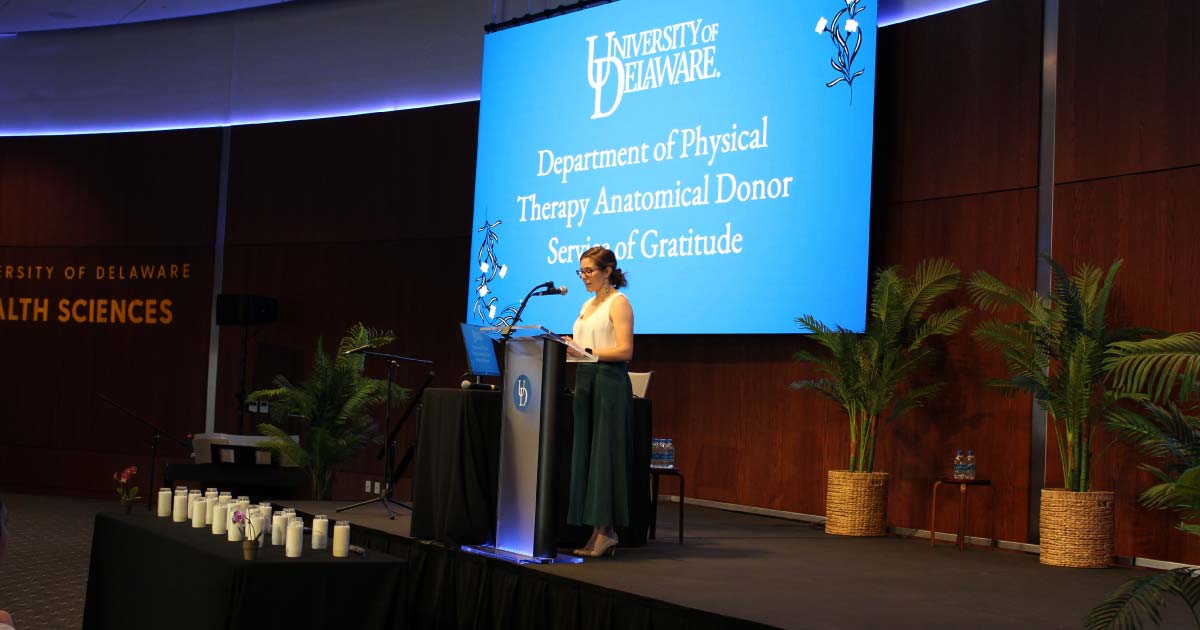 Female student leads presentation at a podium on stage 