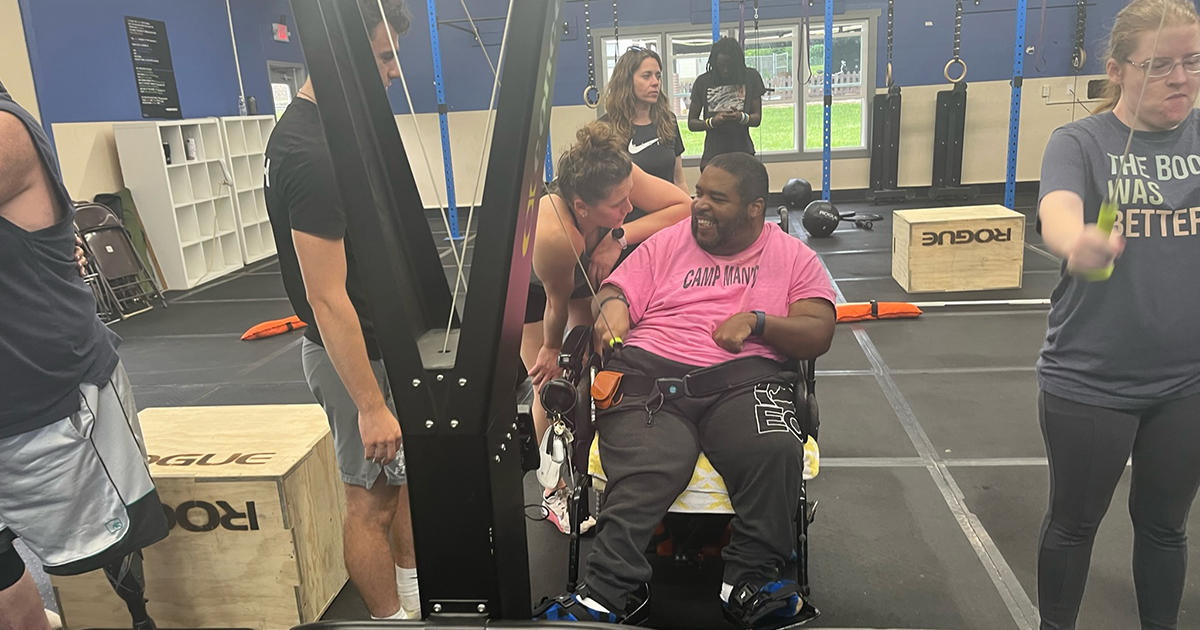A man with cerebral palsy who's in a wheelchair smiles as he works out with UD biomechanics and movement science doctoral student and physical therapist Kiersten McCartney at the Arena Adaptive program at More than Fitness in Wilmington.
