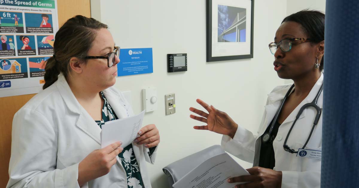 Web Nursing student discusses patient needs with a pharmacy resident in hospital office