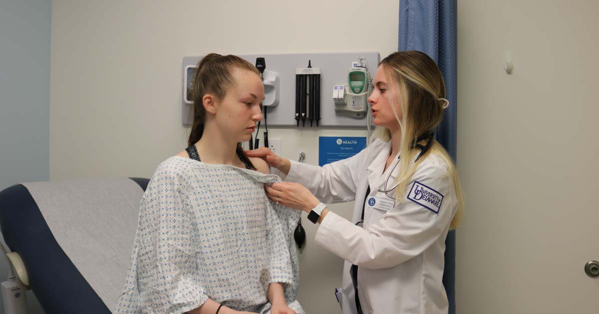 Web Female nursing student examining a patient in a hospital room
