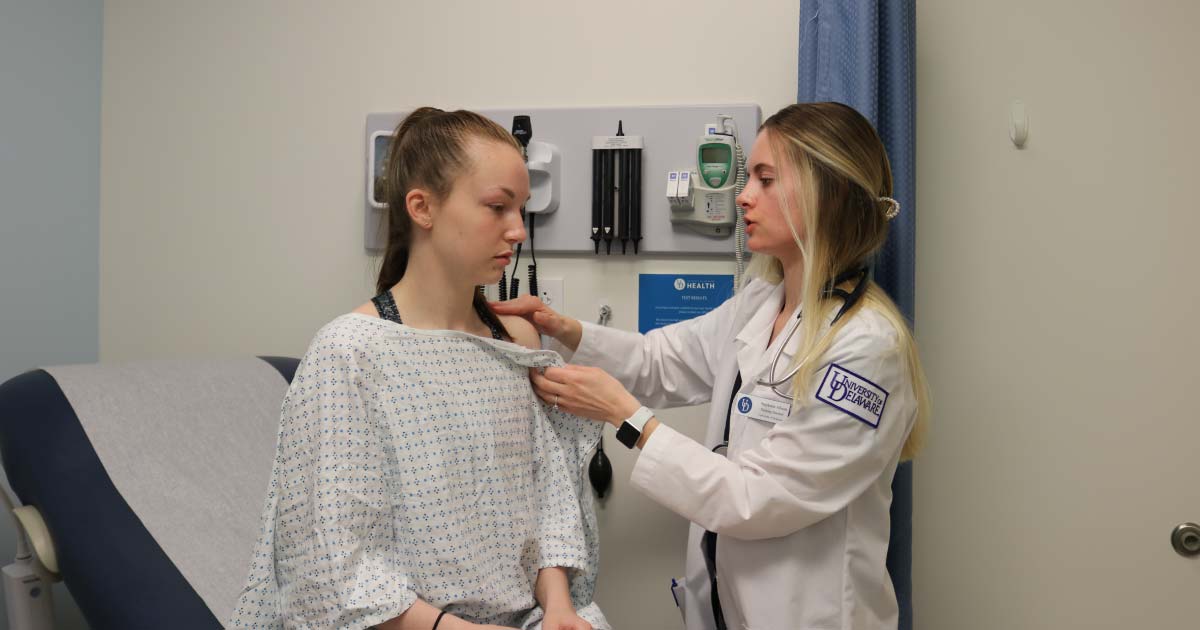 Female nursing student examining a patient in a hospital room 