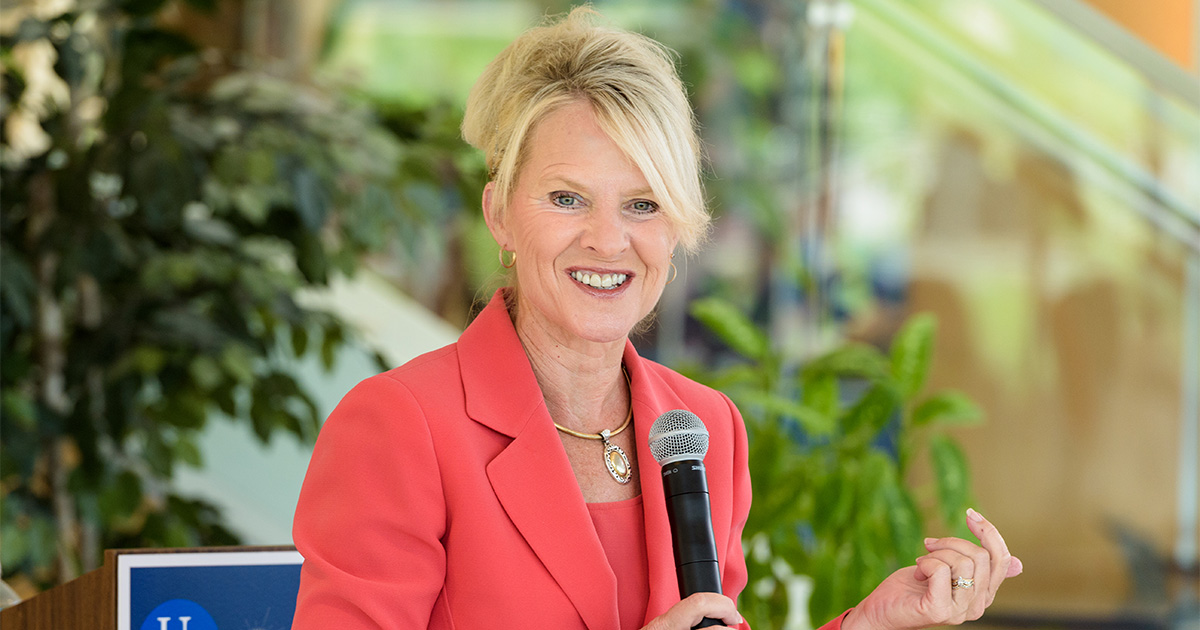 Delaware Lieutenant Governor Bethany Hall-Long, who's also a School on Nursing professor, speaks at a bill signing at the Health Sciences Complex on UD's STAR Campus. Pictured here, she's seen wearing a coral suit with her hair up and holding a microphone.