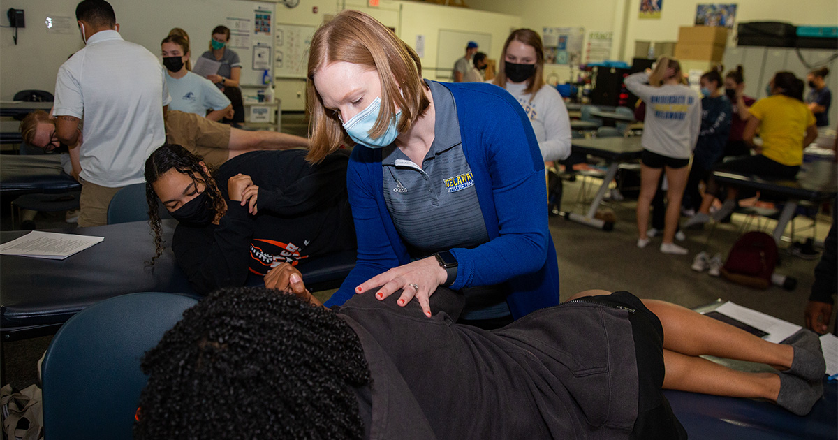Kinesiology and Applied Physiology Assistant Professor Bethany Wisthoff shows students how to stretch in a Sports Health class. 