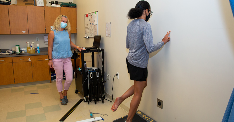 Woman physical therapy professor examining student's foot with health equipment