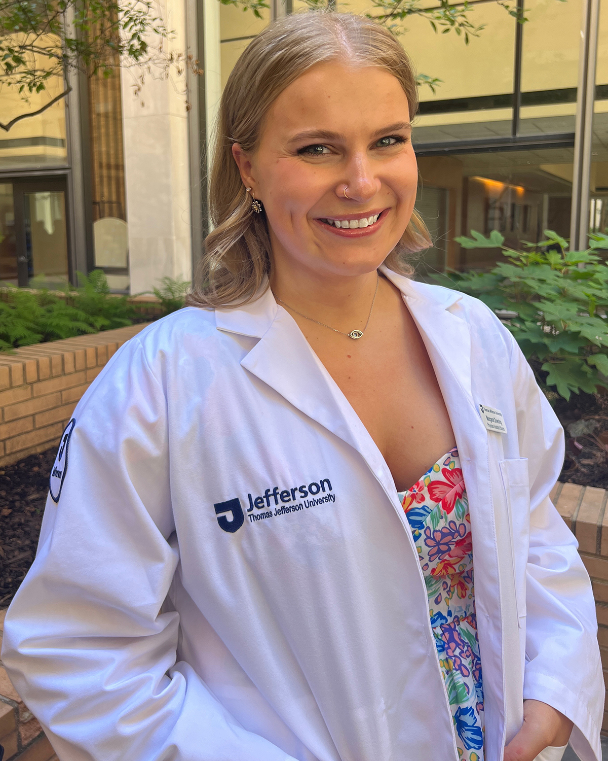 University of Delaware College of Health Sciences alumna dons her white PA coat with Thomas Jefferson University embroidered on it. Downing graduated from Jefferson's PA School in 2023.