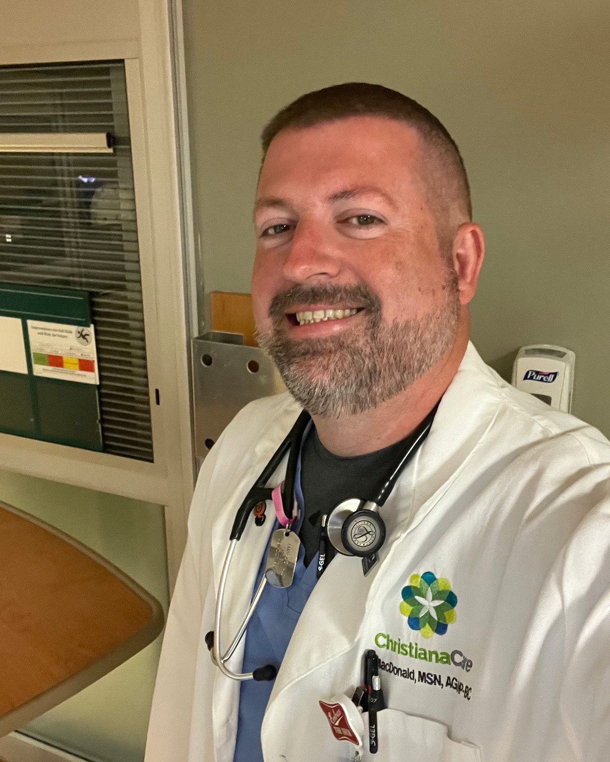A headshot of new School of Nursing Instructor Jason MacDonald wearing his ChristianaCare nursing uniform with a stesthescope around his neck.