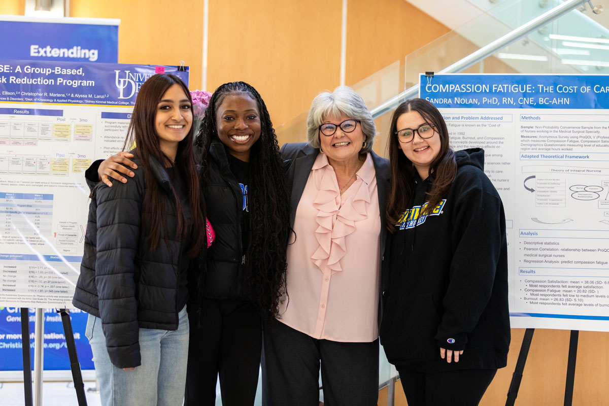 School of Nursing Assistant Professor Sandi Nolan poses with her students in front of her Research Day poster. Her research is on compassion fatigue in nurses early in their careers.