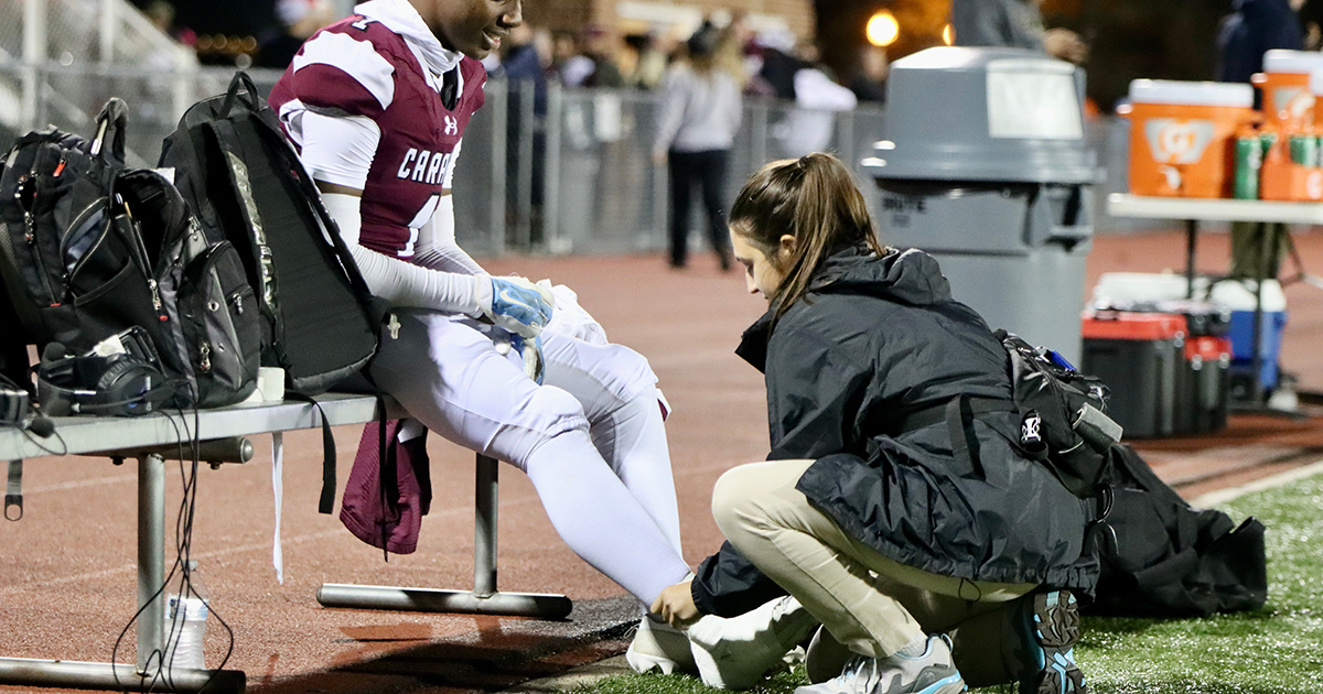 Athletic training master's student Kaley Burgess works on the sidelines helping an athlete with an injury. 