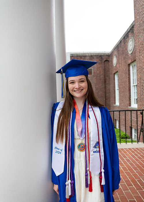 Callista Hofeling, a medical diagnostics major, wears her UD Commencement regalia and poses outside Memorial Hall.