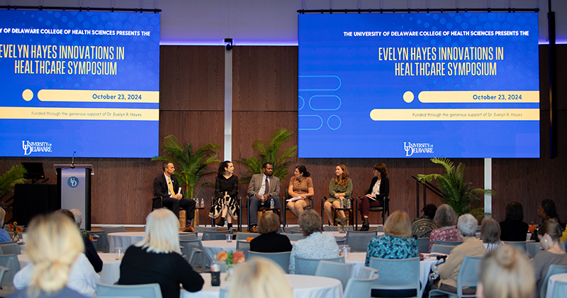 A group of panelists from the community engage in a roundtable discussion on the Audion stage following keynote addresses at the Hayes Symposium. 