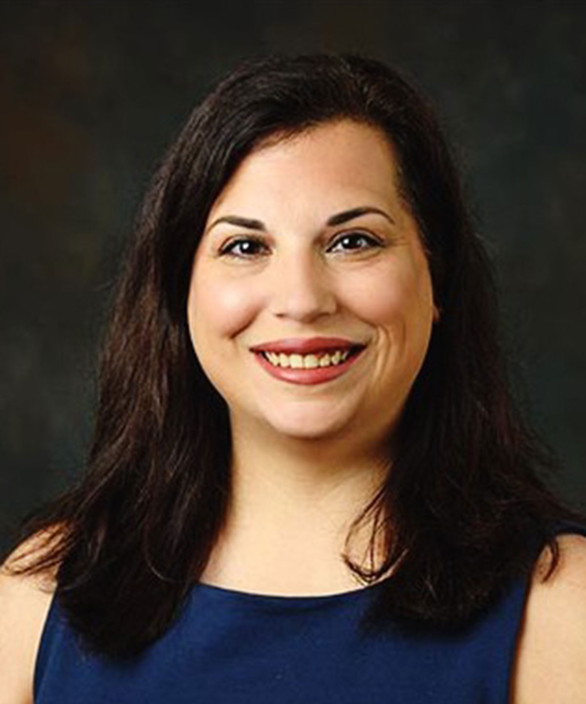 A headshot of Nicole Wilkins with a black background. She's wearing a navy sleeveless top.