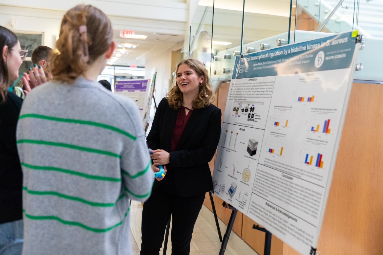 Theresa Edery, a junior honors student majoring in applied molecular biology and biotechnology, presents her research on antibiotic-resistant staph infections. Here, she's seen standing to the side of her poster, talking to Research Day attendees.