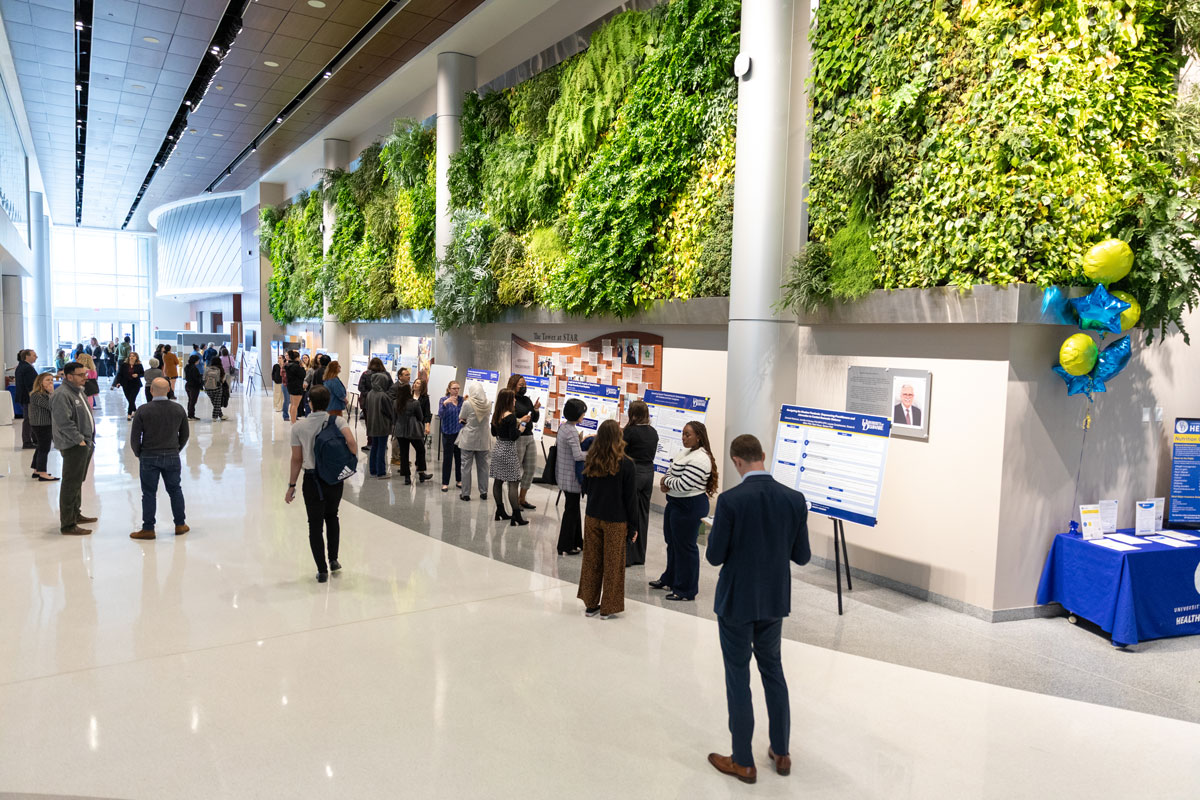 The Atrium hallway showcases the living wall and dozens of research posters on display with Research Day attendees filling the hallways.